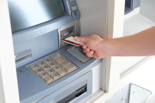 A person inserting a bank card into an atm machine.