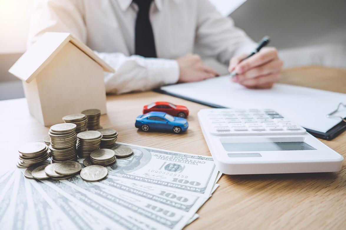 A financial advisor calculating budgets and savings plans with representation of a house, car, and stacks of coins to convey concepts of mortgage, vehicle loans, and personal finance management.