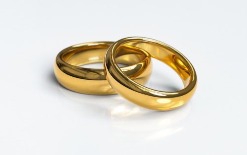 Two golden wedding bands intertwined, symbolizing unity, eternal love, and domestic identity.