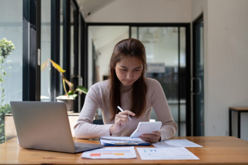 Focused professional analyzing financial reporting at her desk with a laptop and documents.