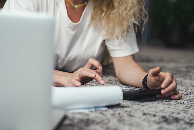 woman on ground with laptop and papers