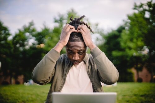 man clutching head in front of computer