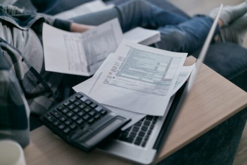 papers on laptop next to calculator