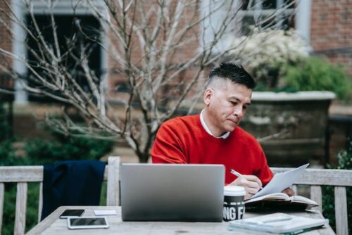 man in front of laptop looking at paper