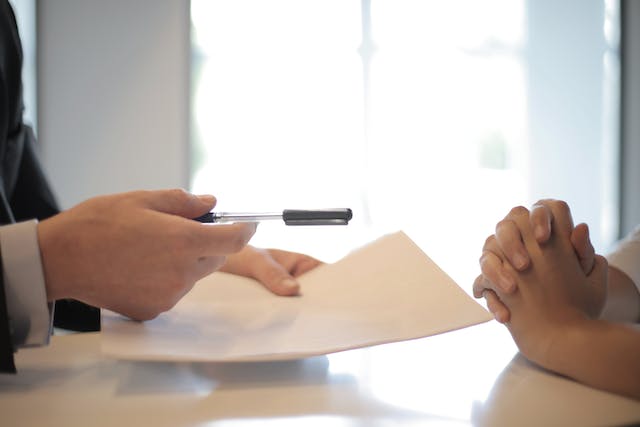 man extending pen and paper