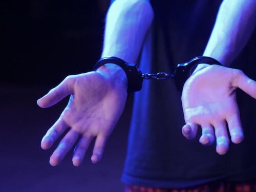 person with hands outstretched and handcuffs