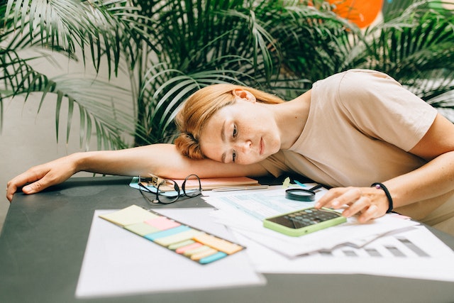 woman laying next to papers and calculator