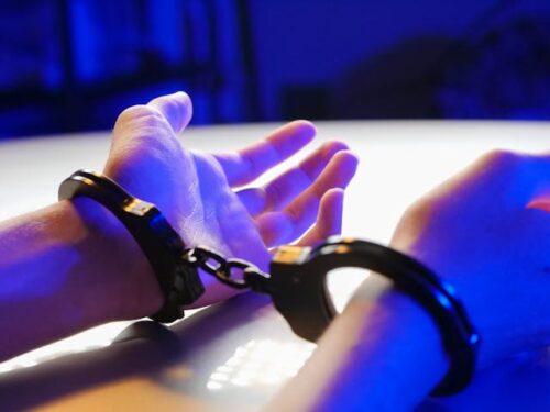 person with hands up in handcuffs