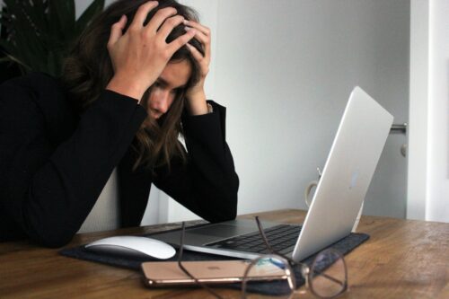 woman clutching head at computer