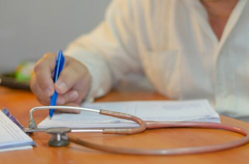 doctor writing note on notepad